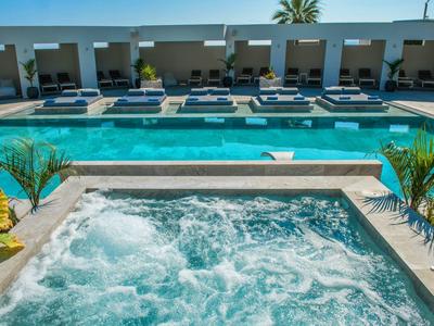 Moderner Außenbereich mit Whirlpool, blauem Schwimmbecken und Liegestühlen unter Sonnendach.