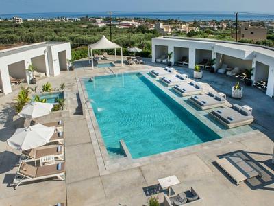 Moderner Außenpool mit Liegestühlen und Blick auf die Küste und Stadt im Hintergrund.