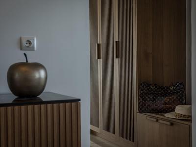 Moderner Flur mit braunen Holzschränken, schwarzer Kommode und großer goldener Deko-Apfel.