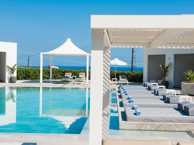 Moderne zwembadzone met ligstoelen en parasols, uitzicht op zee op de achtergrond.