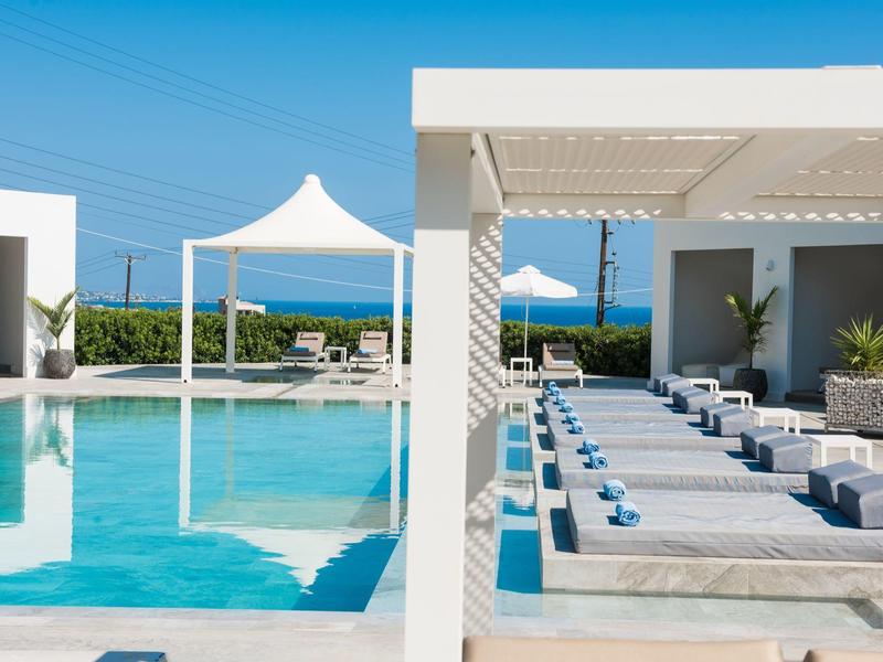 Moderner Poolbereich mit Liegen, Sonnenschirmen und klarem blauem Wasser, sonniger Tag.