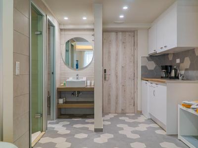 Moderní světlá koupelna s umyvadlem, kulatým zrcadlem a samostatnou sprchou.