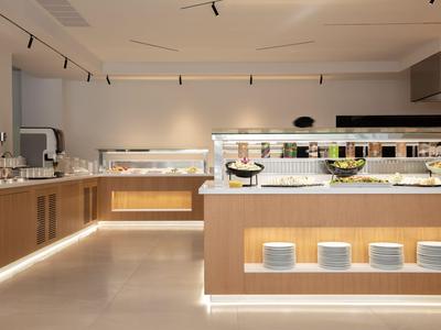 Moderní hotelový bufet s osvětlením a bohatým výběrem nádobí a jídel.