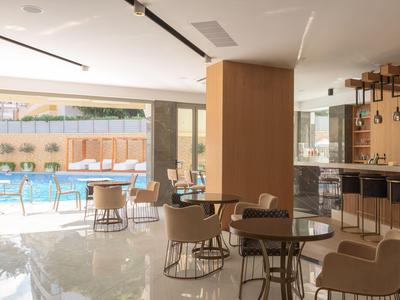 Moderní hotelový salonek s posezením a výhledem na venkovní bazén za denního světla