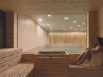 Žena relaxuje v moderní dřevěné sauně s nepřímým osvětlením.