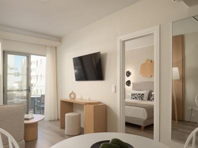Modern furnished hotel room with TV, sofa, and balcony view.