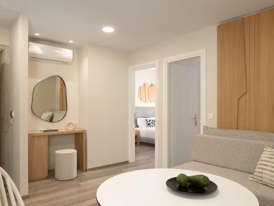 Jasny pokój hotelowy z przytulnym miejscem do siedzenia, okrągłym stołem i nowoczesną łazienką w tle.