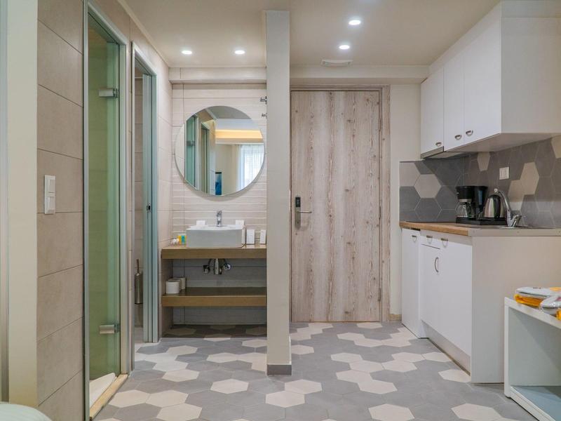 Moderní světlá koupelna s umyvadlem, kulatým zrcadlem a samostatnou sprchou.