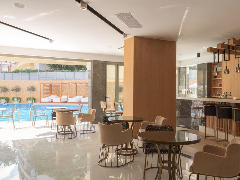 Moderní vnitřní prostor s posezením a výhledem na venkovní bazén.