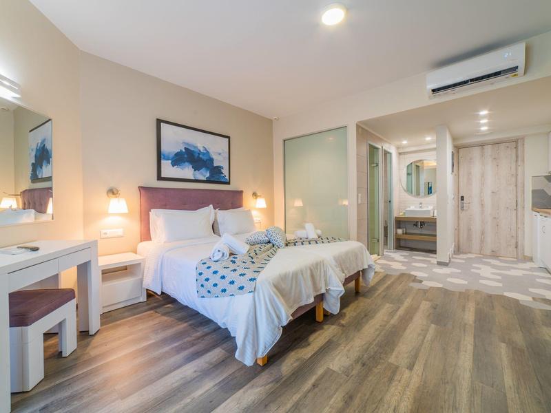 Moderní hotelový pokoj se dvěma jednolůžky, psacím stolem a dřevěnou podlahou.