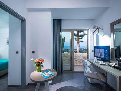 Modernes Zimmer mit blauem Bett, kleinem runden Tisch, Balkon und Meerblick.