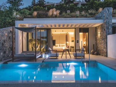 Modernes Haus mit großen Glasfronten, beleuchtetem Pool und gemütlicher Terrasse am Abend.
