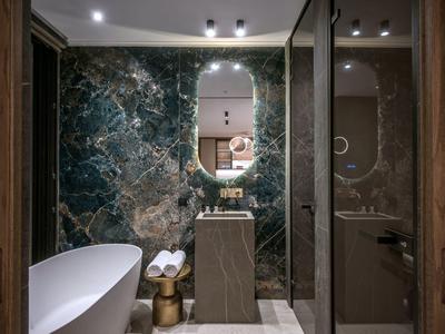 Modernes Badezimmer mit freistehender Badewanne, Marmorwand und ovalem Spiegel.