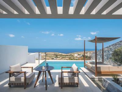 Moderne Terrasse mit Pool, Holzliegen, Pergola und Blick aufs blaue Meer unter blauem Himmel.