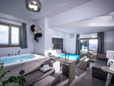 Modern hotel room with whirlpool, bed, sofa, and sea view through large windows