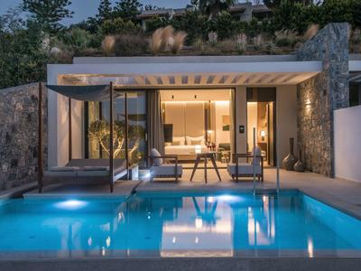 Modern holiday home with illuminated pool and cozy terrace at night