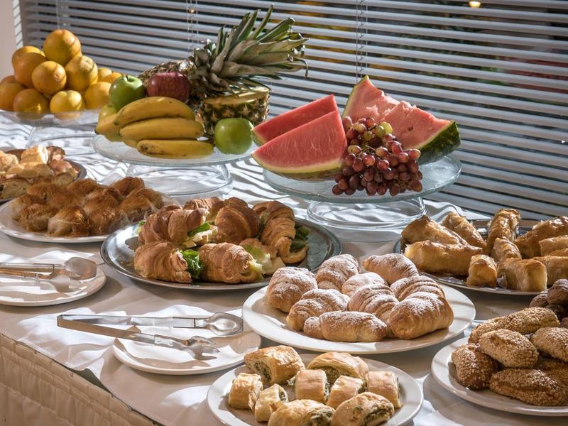 Buffet with various pastries, fruits, and croissants on a table with white tablecloths.