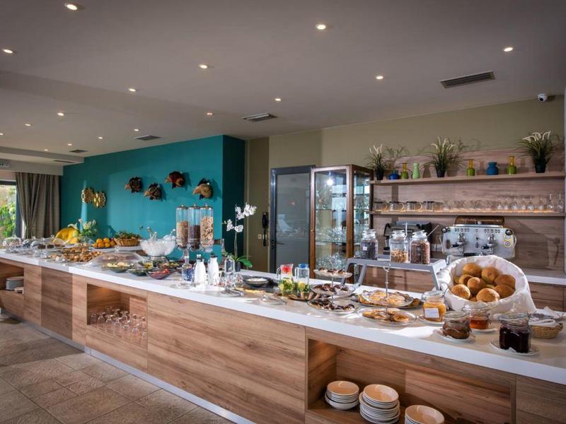 Buffet with a variety of pastries and breakfast items in a modern hotel dining area.