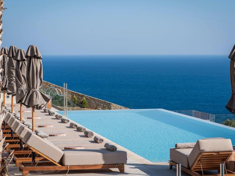 Infinity pool with loungers and umbrellas overlooking the sea.