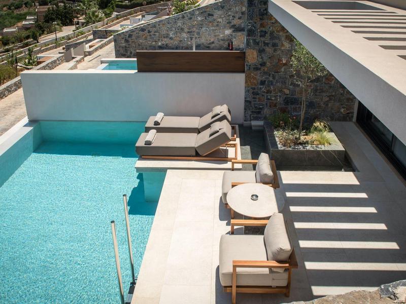 Modern outdoor pool with sun loungers and seating area at a luxury accommodation.