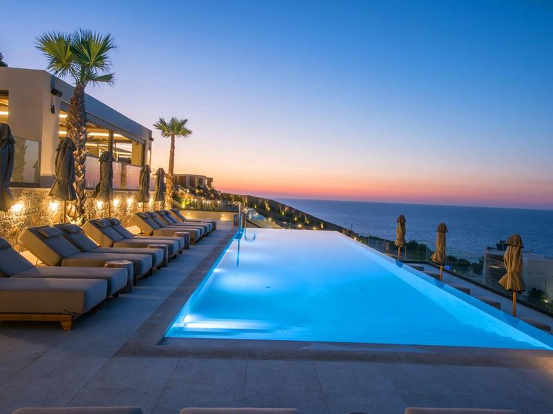 Infinity pool at sunset with lounge chairs and sea view in a luxury hotel.