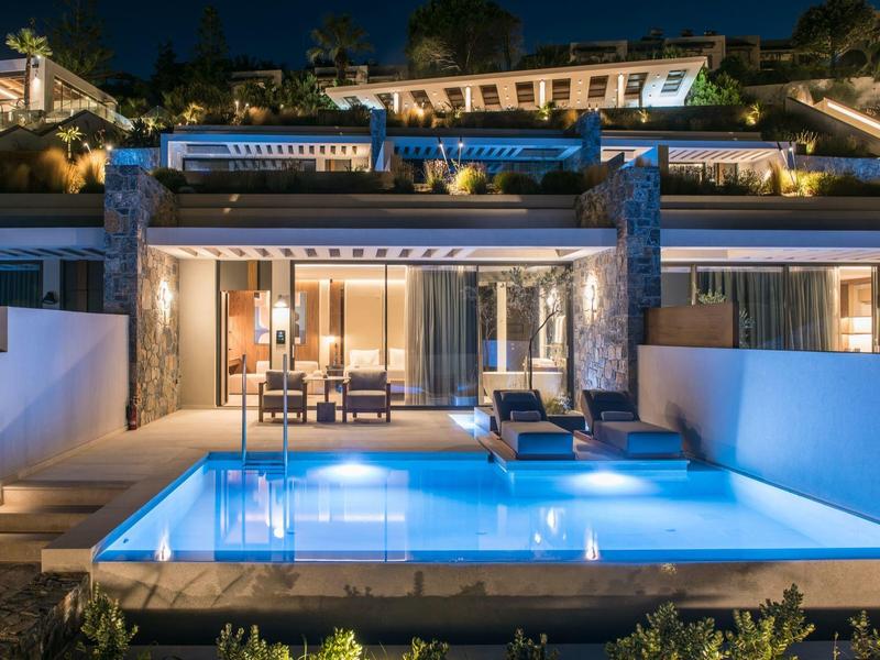 Modern house with illuminated pool and terrace at night.