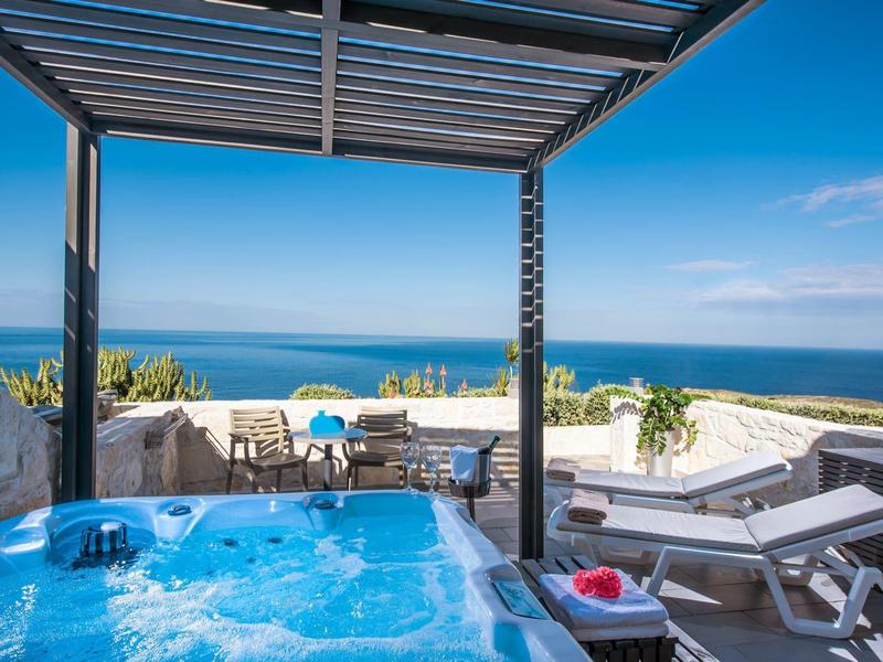 Hot tub on a terrace overlooking the sea under a clear sky.