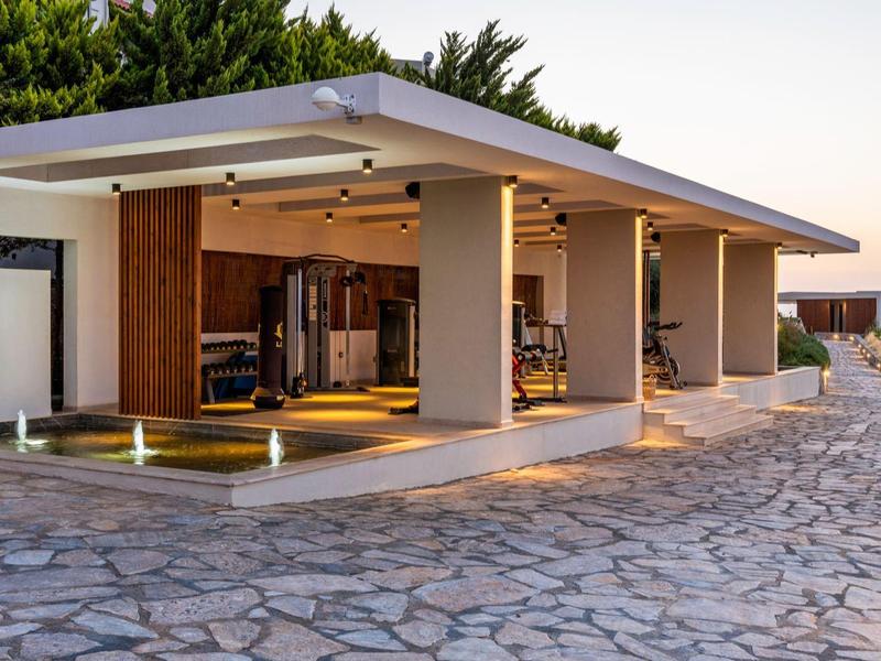 Modern open house with large covered living area and stone terrace at sunset