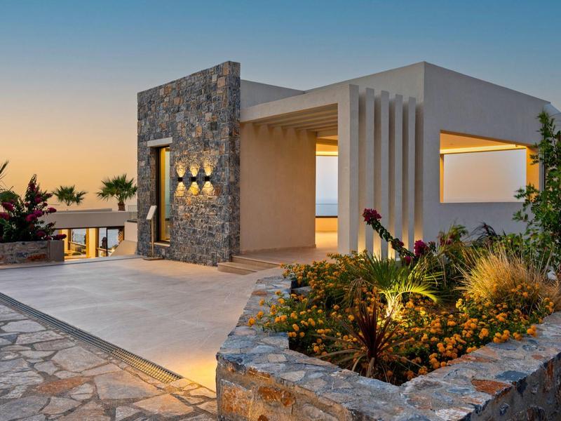 Modern house with stone accents and garden lighting at sunset