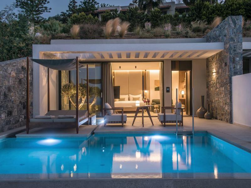 Modern holiday home with illuminated pool and cozy terrace at night