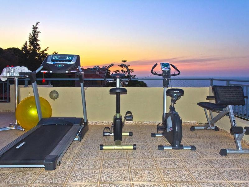 Exercise equipment on a terrace with sea view at sunset.