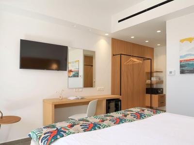 Chambre d'hôtel lumineuse avec lit, literie colorée et mobilier moderne.