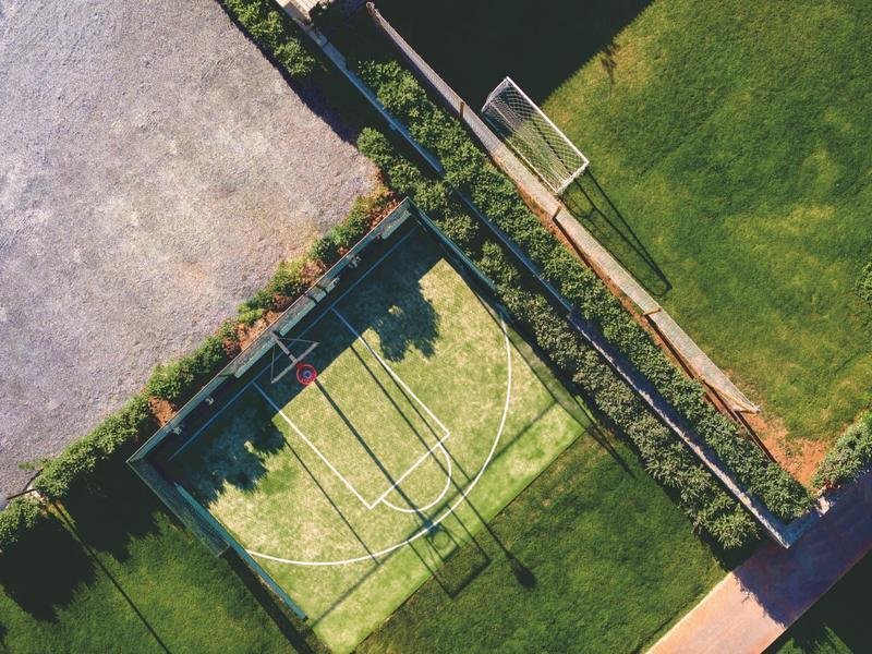 Zewnętrzne boiska sportowe z bramką do piłki nożnej na zielonej trawie i ogrodzone boisko wielofunkcyjne.