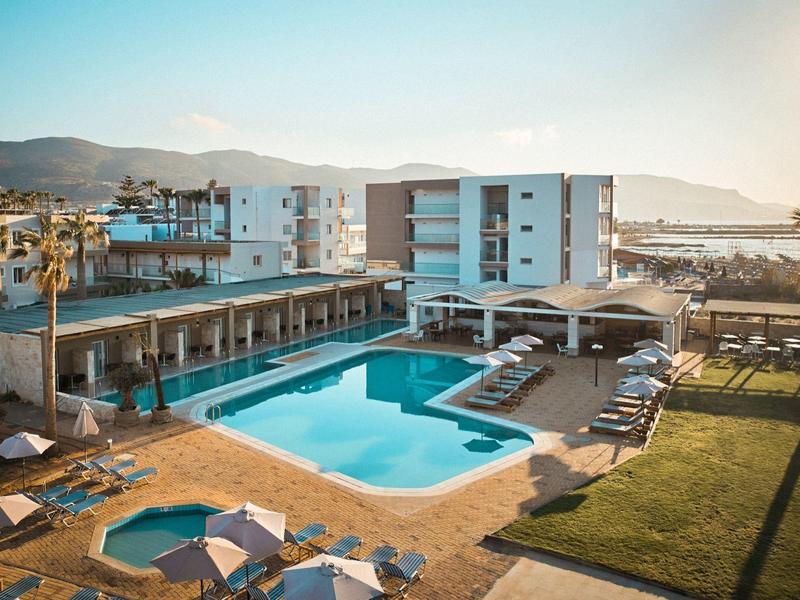 Moderner Außenpool mit Liegestühlen, Sonnenschirmen und Mehrstöckigen Gebäuden im Hintergrund.