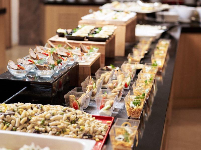 Buffet mit verschiedenen Salaten und Getränken in Gläsern, modern und einladend arrangiert.