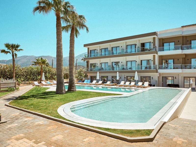 Moderner Hotelpool mit Liegestühlen, Palmen und klar blauem Himmel in sonniger Umgebung.