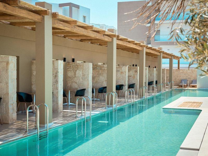 Moderner Außenpool mit Liegen, Schattenplätzen und hellem Steinmauer-Design in klarem Wasser.