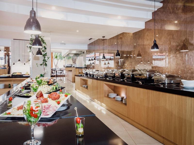 Buffet mit frischem Gemüse, Salaten und warmen Speisen in modernem, hellen Restaurant.