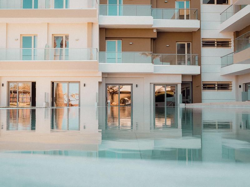 Moderner Wohnkomplex mit glatten weißen Wänden und klarem Pool im Vordergrund bei Tageslicht.