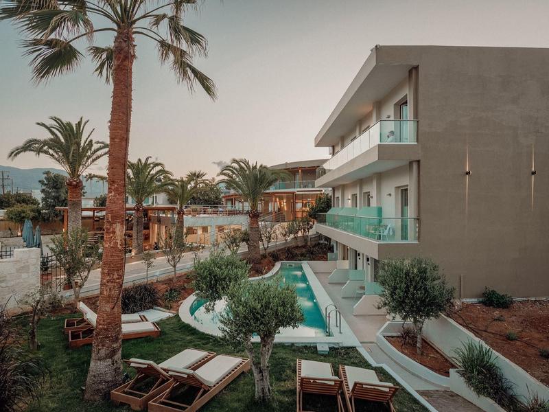 Modernes Haus mit Pool, Palmen und Liegestühlen in ruhiger, grüner Umgebung bei Abendlicht.