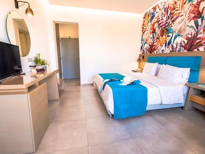 Camera d'albergo moderna con letto matrimoniale, parete decorata colorata e televisore su mobile.