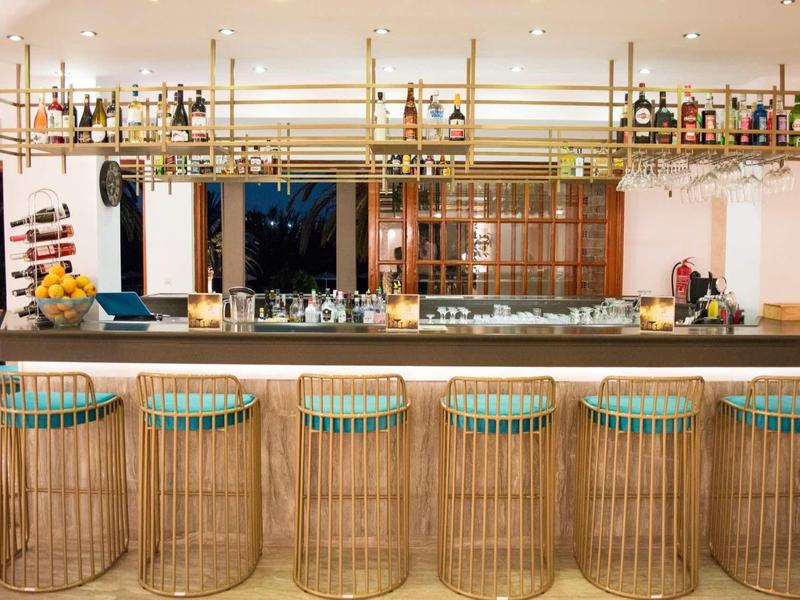 Nowoczesny bar hotelowy z bambusowymi stołkami i wiszącymi półkami z butelkami.