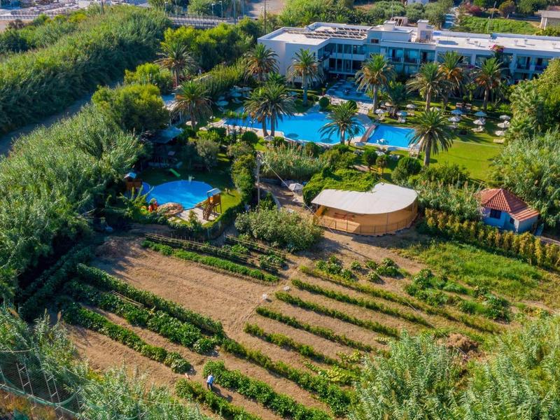 Widok z lotu ptaka na ośrodek z dużymi basenami, bujnymi ogrodami i przyległymi polami uprawnymi.