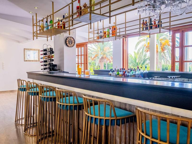 Nowoczesny hotelowy bar z drewnianymi stołkami i kolorowymi akcentami w jasnym pomieszczeniu z oknami.