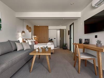 Modern hotelkamer met bank, tafel, bureau en tv.