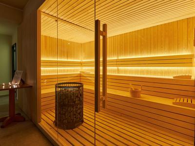 Moderne sauna met houten bekleding en glazen wand in een wellnessruimte.