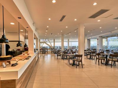 Modern, helder restaurant met gedekte tafels en grote ramen in een hotelomgeving.