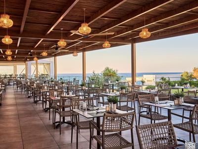 Covered terrace with many tables and chairs overlooking the sea.