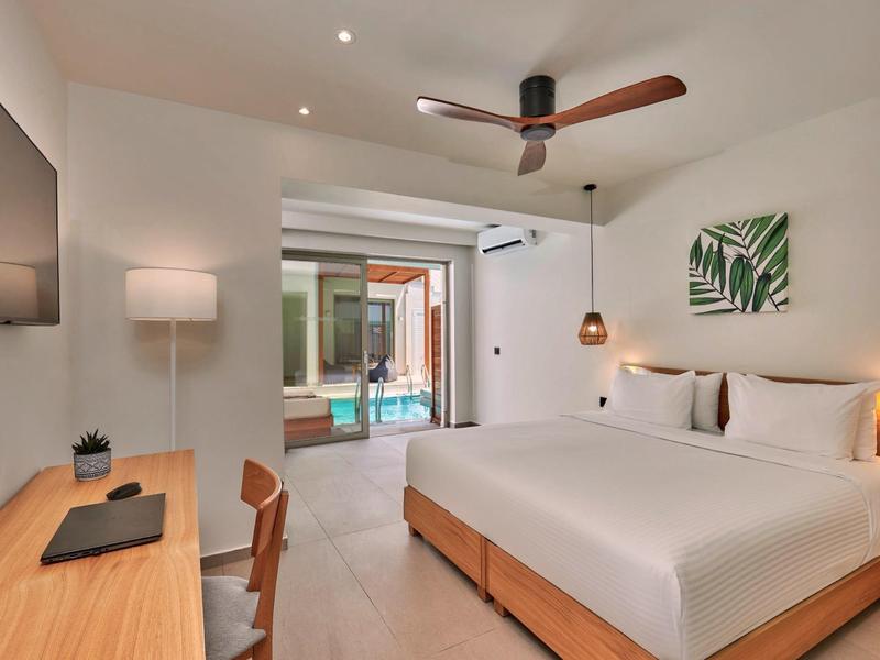 Moderne hotelkamer met tweepersoonsbed, bureau en toegang tot een terras met uitzicht op het zwembad.