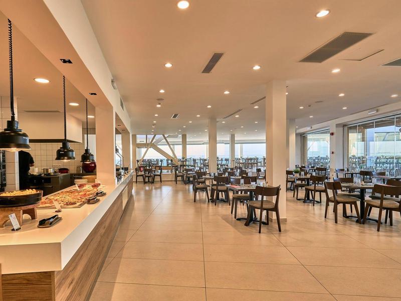 Modern, helder restaurant met gedekte tafels en grote ramen in een hotelomgeving.